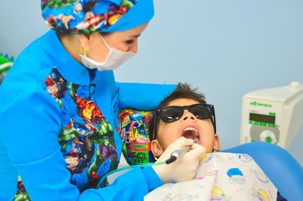 a dentist in blue performing a dental check-up on her patient