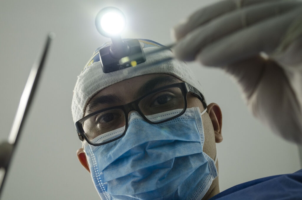 photo of a dentist with dental loupes on his forehead used to help check his patient's dental health