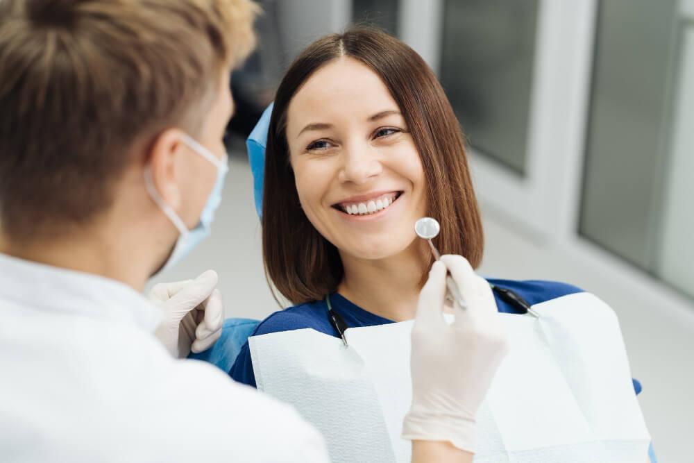 dentist white white gloves holding a dental mirror with a smiling patient on a dentist chair